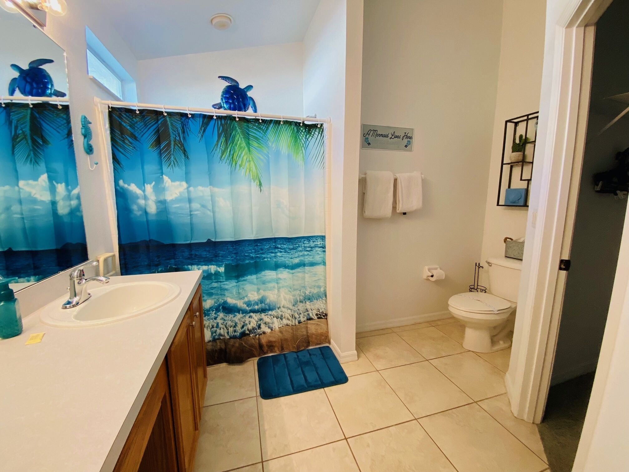 A bathroom with a sea-themed shower curtain, a sink, and a toilet.