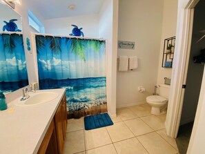 A bathroom with a sea-themed shower curtain, a sink, and a toilet.