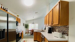 Une cuisine moderne avec des meubles en bois, des appareils électroménagers en acier inoxydable et un dosseret carrelé.