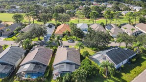 A residential area with houses, green lawns, and a body of water in the background.