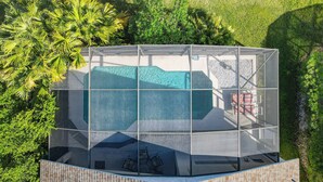 An aerial view of a modern building with a swimming pool, surrounded by lush greenery.