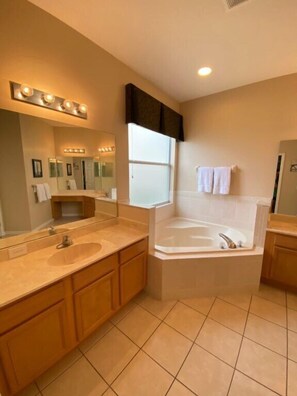 A modern bathroom with two sinks, a large mirror, and a bathtub.
