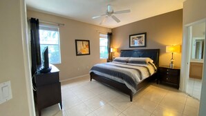 Une chambre à coucher avec un lit, un bureau, un ventilateur de plafond et une fenêtre.