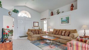 A spacious living room with two sofas, a coffee table, and a striped armchair. - Maria's Southern Dunes Vacation Home (Haines City)