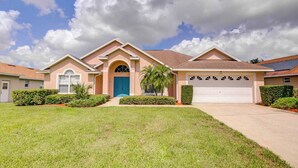 A two-story house with a blue front door, a garage, and a well-maintained lawn. - Maria's Southern Dunes Vacation Home (Haines City)