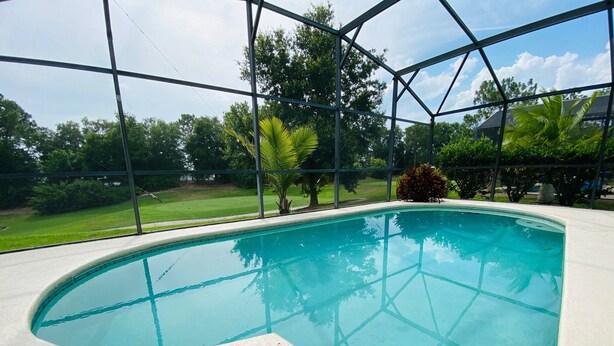 An indoor swimming pool with a clear view of the surrounding landscape through large windows. - Dennis' Southern Dunes Vacation Home (Haines City)