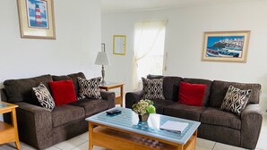 A living room with two sofas, a coffee table, and a lamp. There are framed pictures on the walls. - Dennis' Southern Dunes Vacation Home (Haines City)