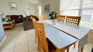 A dining area with a table, chairs, and a vase of flowers. - Dennis' Southern Dunes Vacation Home (Haines City)