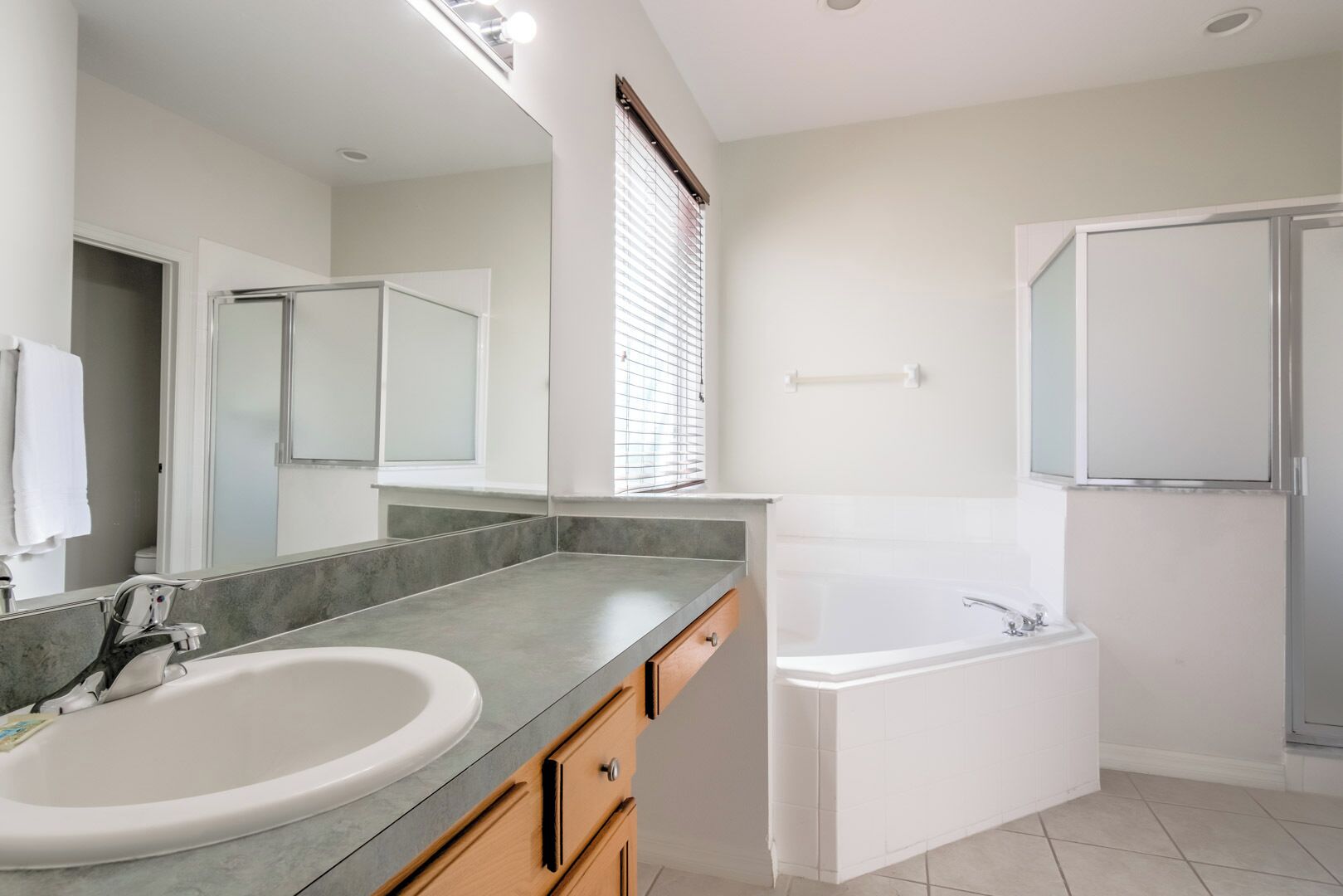 Un bagno moderno con doppio lavabo, vasca da bagno e un grande specchio.