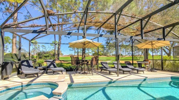 Un espace extérieur abrité comprenant une piscine, des chaises longues, des parasols et un barbecue.