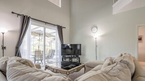 Un salon moderne avec un grand canapé, un téléviseur à écran plat et une table de barbecue.