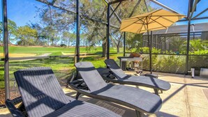 Un espace extérieur aménagé avec des meubles de jardin en osier et un barbecue, offrant une vue sur un terrain de golf.
