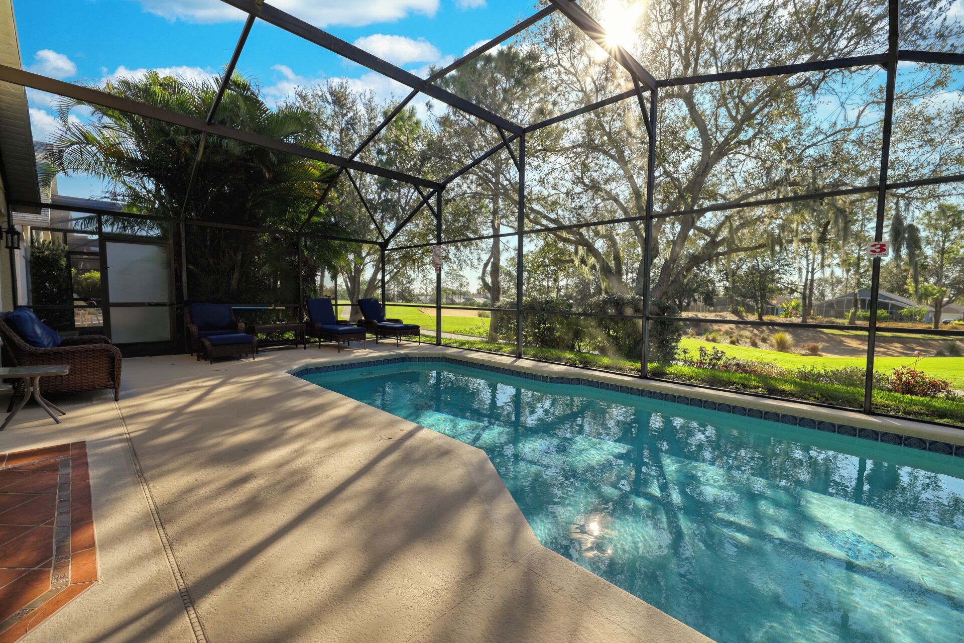 An indoor swimming pool with a glass enclosure, surrounded by lounge chairs and a patio area.