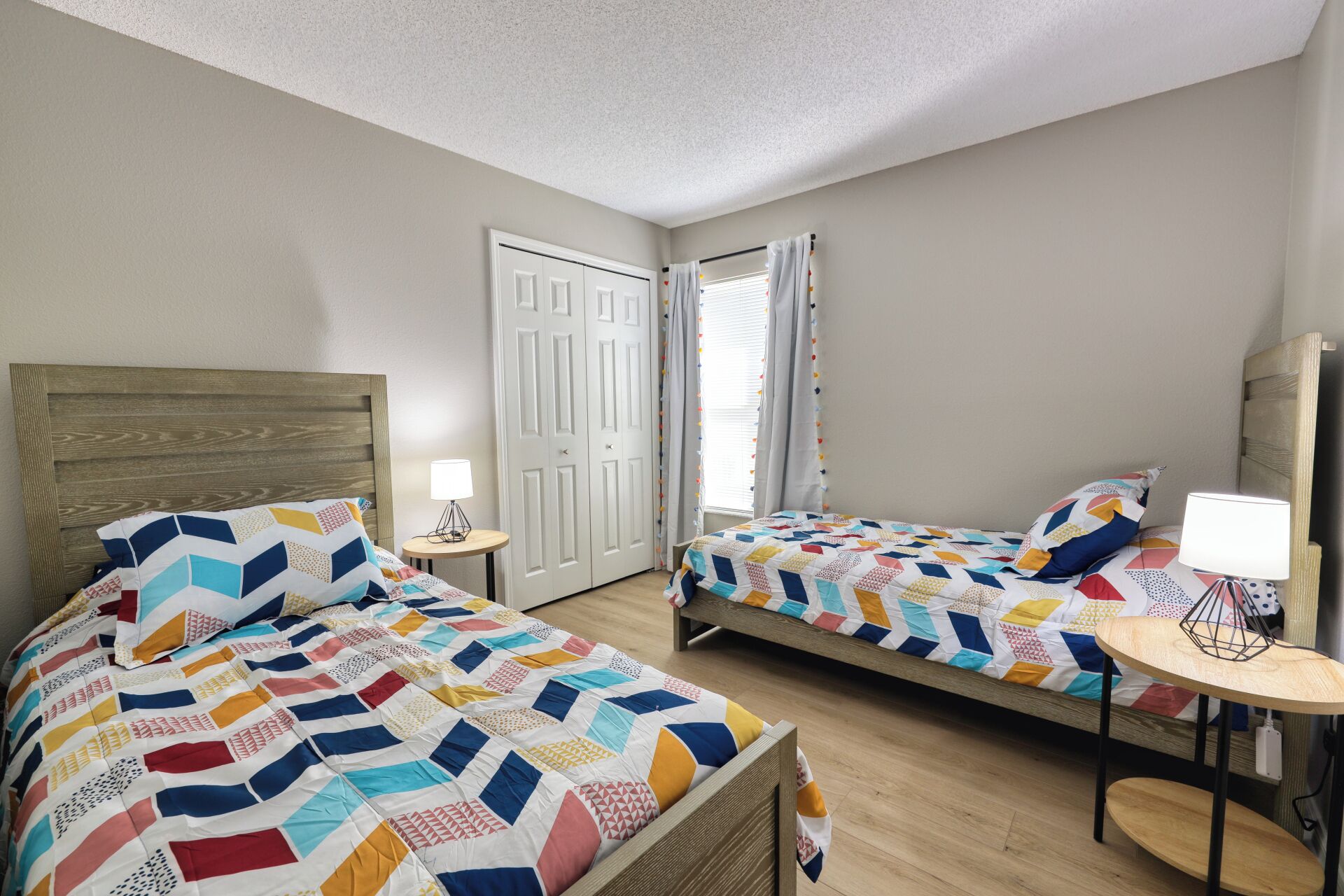 A hotel room with two beds, a small table, and a door.