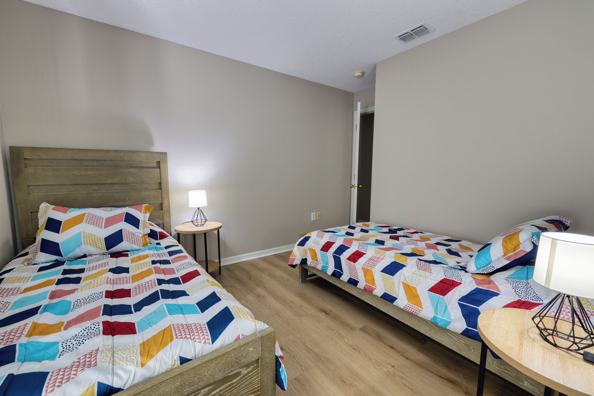 A room with two beds, a small round table, and a door leading to another room.