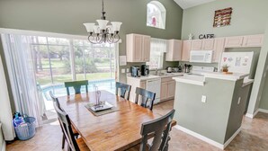 A spacious kitchen with a dining area, large windows, and a view of a backyard.