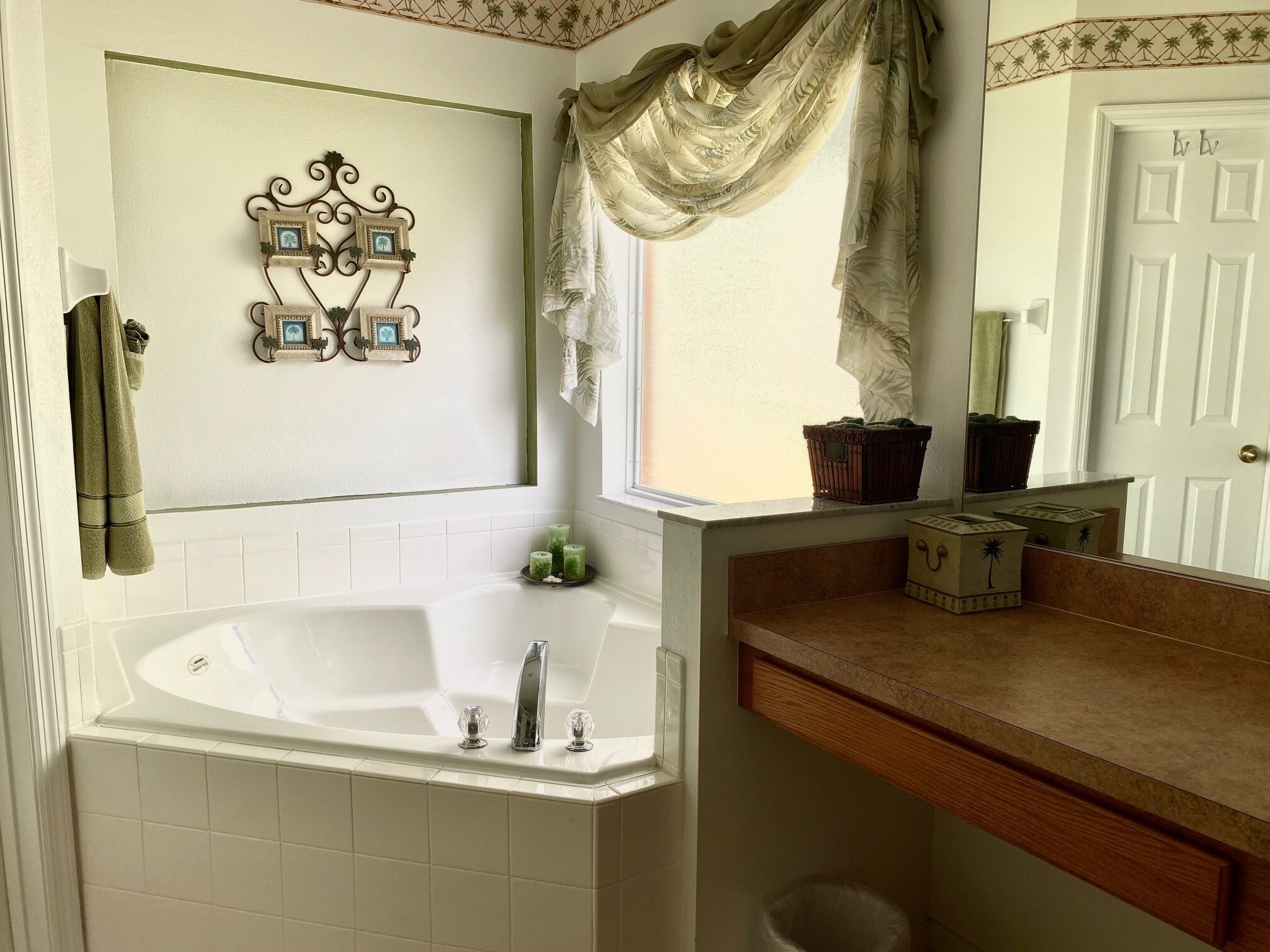 A bathroom with a bathtub, a vanity with a mirror, and a window with curtains.
