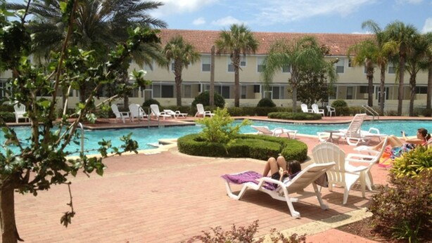 A pool area with lounge chairs and palm trees. - Lake View Townhome Near Disney (Kissimmee)
