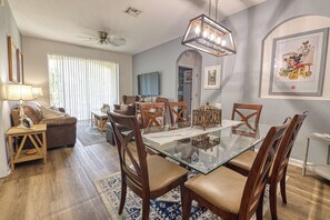 A dining area with a glass table and wooden chairs, a ceiling fan, and a framed picture on the wall. - Amazing Condo in Windsor Hills - Close to Disney (Kissimmee)
