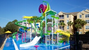 Een waterpark met verschillende glijbanen en waterattracties, omgeven door gebouwen.