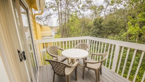 Eine Holzterrasse mit weißer Geländer, einem runden Tisch und vier Stühlen.