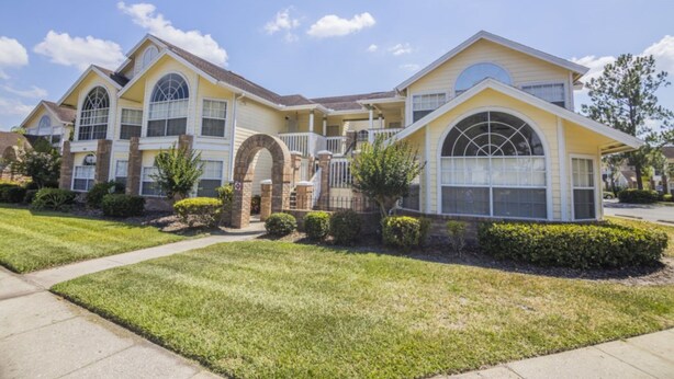 A large, yellow two-story house with a spacious front yard, a driveway, and a garage. - Laguna Bay 007 (Kissimmee)
