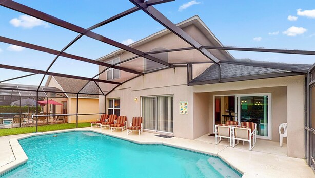 A swimming pool with lounge chairs and a covered patio area. - William's Lake Berkley Resort Vacation Home (Kissimmee)