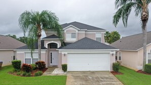 A two-story house with a garage, surrounded by well-maintained lawns and palm trees. - William's Lake Berkley Resort Vacation Home (Kissimmee)