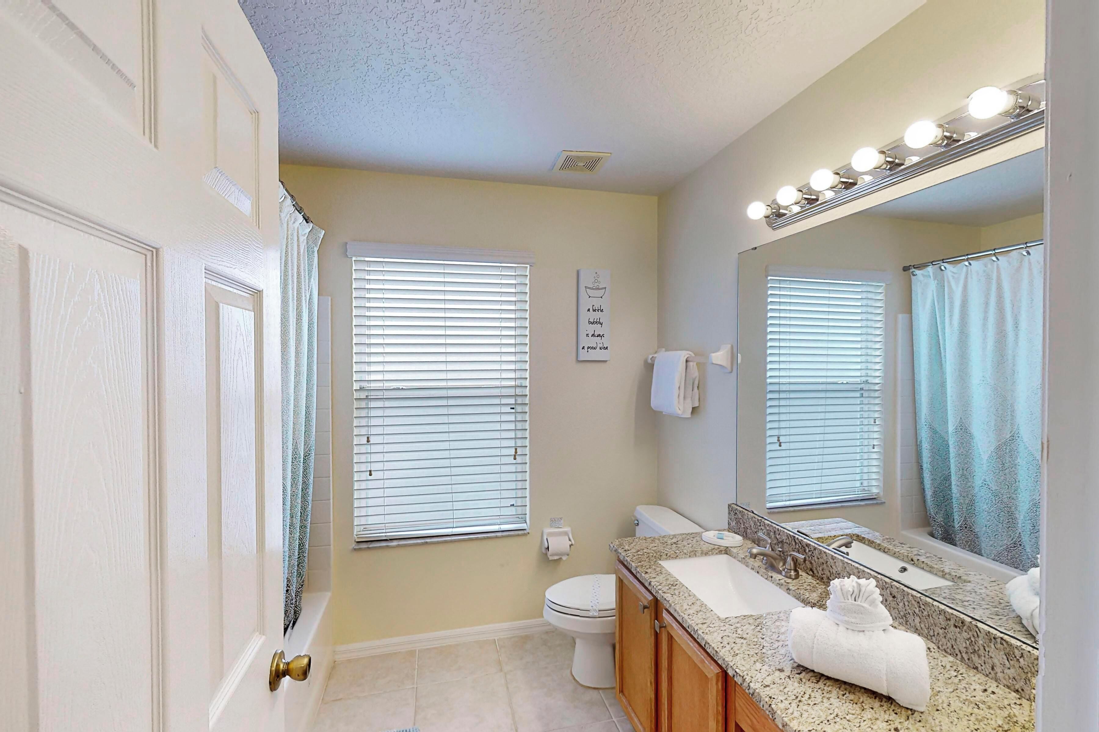 A bathroom with a white door, a toilet, a sink with a mirror, and a towel rack.