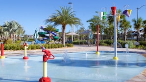 A water park with a large pool, water jets, and a water slide in the background. - Brenda's Storey Lake Resort Townhome (Kissimmee)