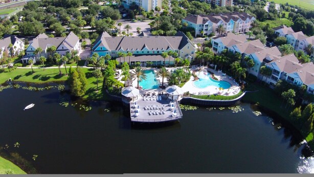 An aerial view of a resort with a central pool, a dock, and surrounding villas. - James' Runaway Beach Condo (Kissimmee)
