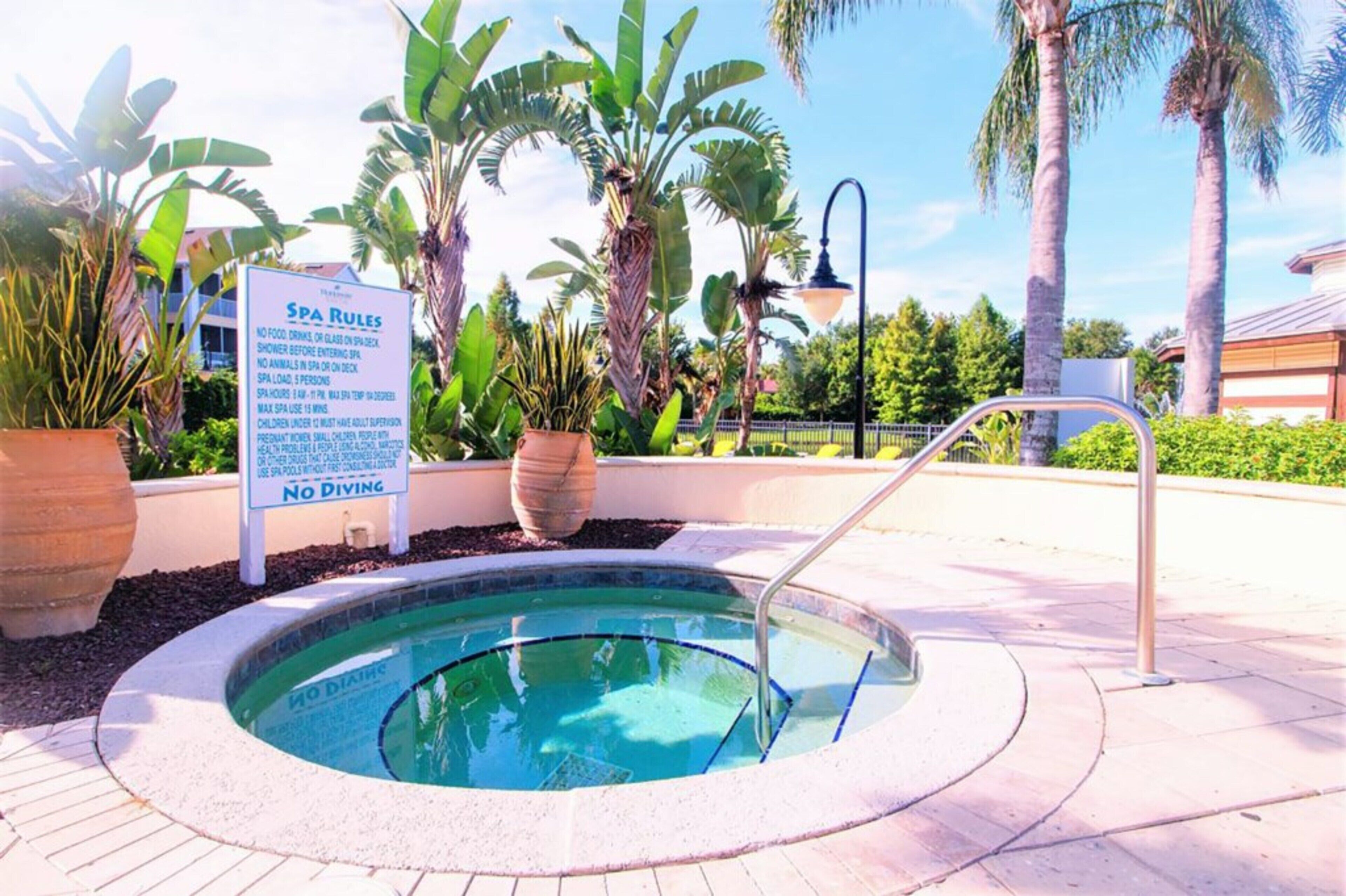 A pool area with a sign listing spa rules and a 'No Diving' sign.