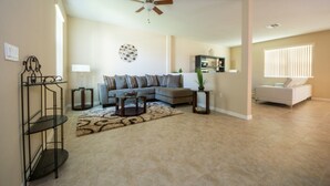 A living room with a gray sofa, a coffee table, a floor lamp, and a ceiling fan. - Anastasia's Crystal Cove Vacation Home (Kissimmee)