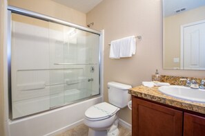 Une salle de bain avec une douche à parois de verre, des toilettes, un lavabo et des meubles en bois.