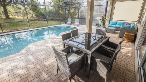 A covered outdoor area with a pool, wicker furniture, and a sofa. - Bernard's Windsor Hills Resort Vacation Home (Kissimmee)