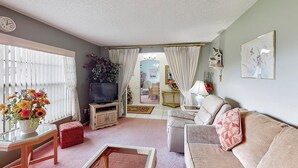 A living room with a television, sofa, and a dining area in the background.