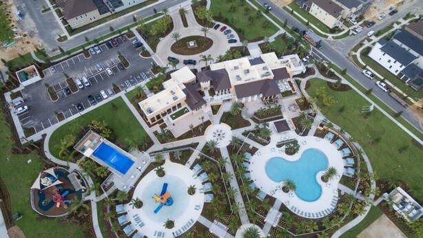 An aerial view of a residential area with a central circular pool, a smaller pool, and a playground. - Jodie's Luxury Solara Home (Kissimmee)
