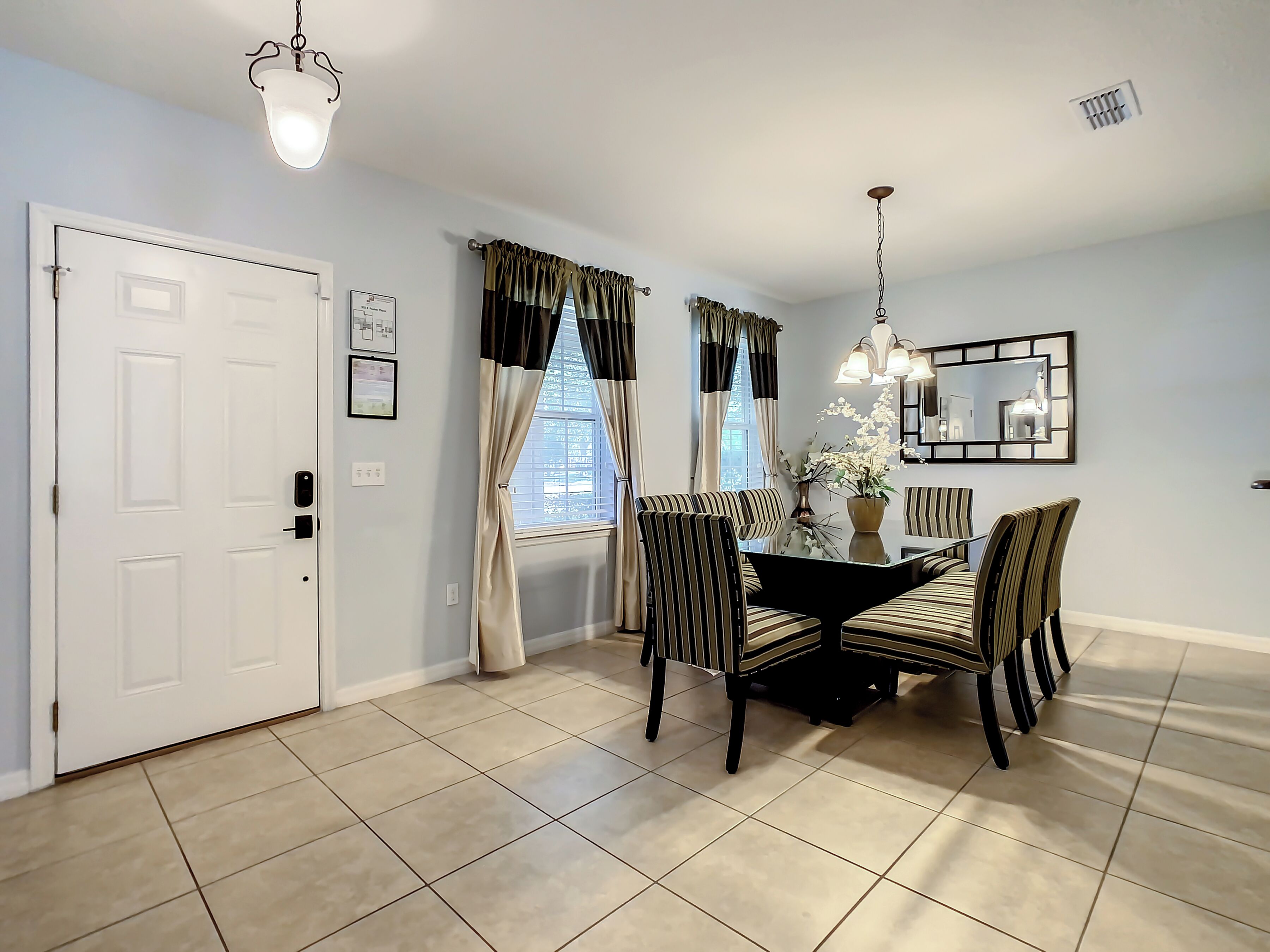 A dining area with a table and chairs, a door, and a window with curtains.