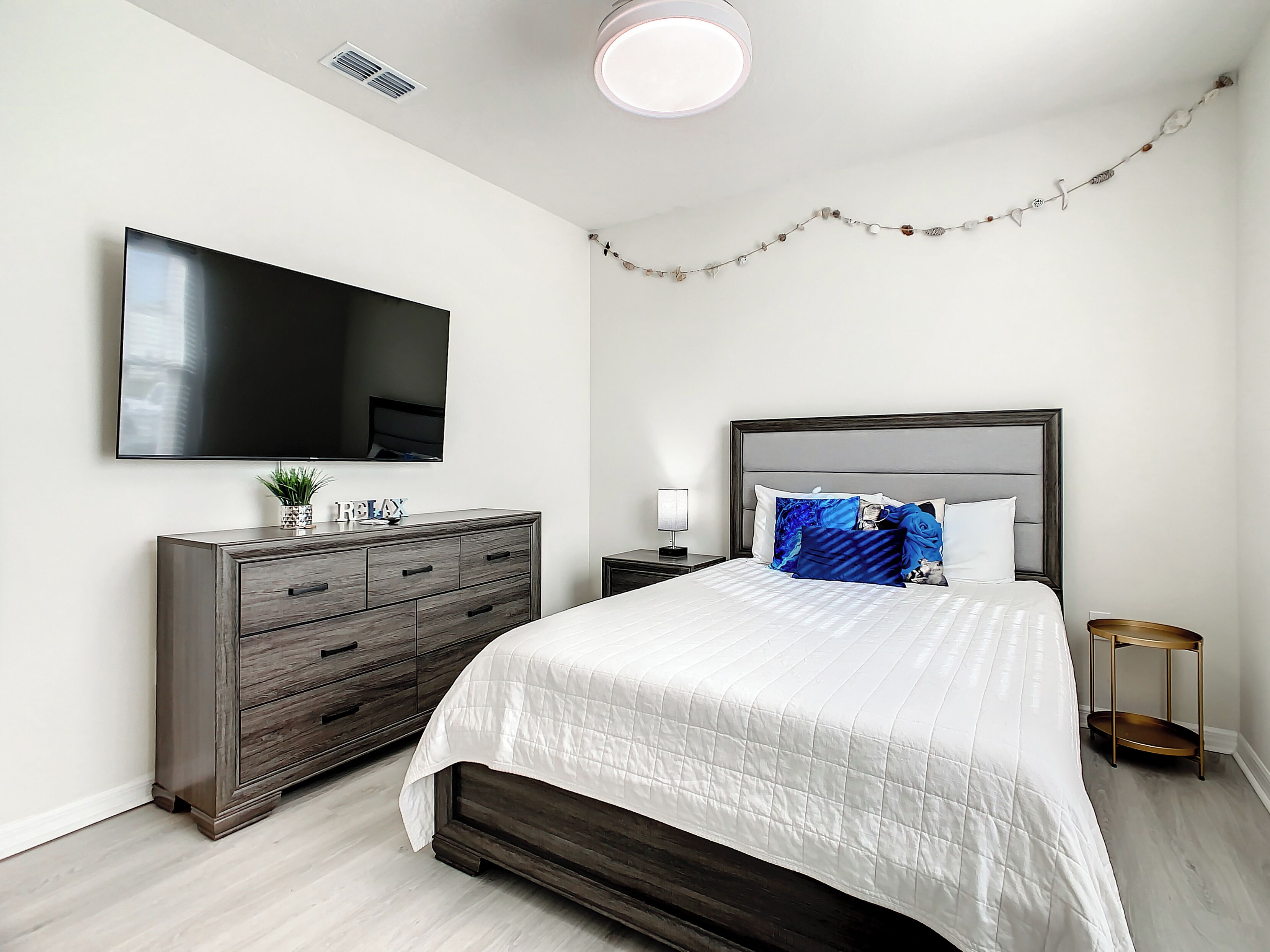 A bedroom with a bed, a dresser, a TV, and a nightstand.