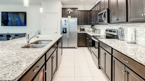 A modern kitchen with granite countertops, stainless steel appliances, and dark wooden cabinets. - A Touch of Blue at Windsor Island Resort (Davenport)