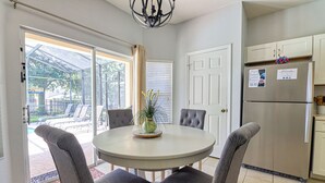 A kitchen with a round table, four grey chairs, a stainless steel refrigerator, and a door with a sign. - Christopher's Windsor Hills Home (Kissimmee)