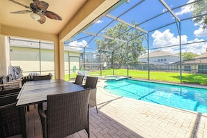 A covered outdoor area with a pool, wicker furniture, and a ceiling fan. - Christopher's Windsor Hills Home (Kissimmee)