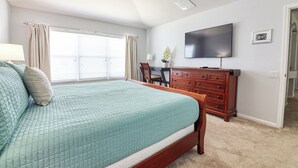 A bedroom with a bed, a desk, a dresser, a television, and a window with curtains. - Christopher's Windsor Hills Home (Kissimmee)