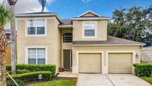 A two-story house with a front garage, a covered entryway, and a well-maintained lawn. - Comrow Castle Magical Getaway (Kissimmee)