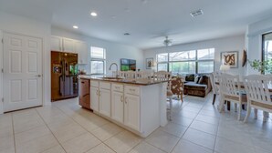 A spacious kitchen with white cabinetry, a large island, and a dining area with white chairs and a table. - Beautiful Providence Vacation Home (Davenport)