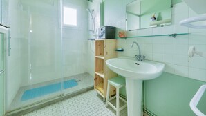A bathroom with a glass shower enclosure, a white sink, and a mirror above it.