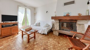 A living room with a fireplace, a sofa, a television, and a wooden cabinet.