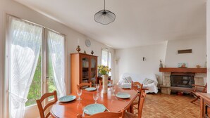 A dining area with a wooden table set for four, surrounded by chairs, a wooden cabinet, and a fireplace.