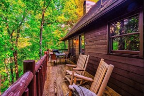 Una terraza de madera con una mesa y sillas, rodeada de árboles.