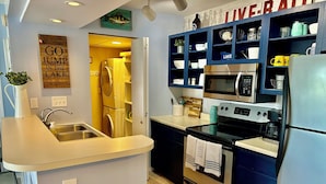 Une petite cuisine  équipée d’un évier, d’une cuisinière et d’un four à micro-ondes. Une pancarte sur le mur porte l’inscription : « VIVEZ. RESPIREZ. »